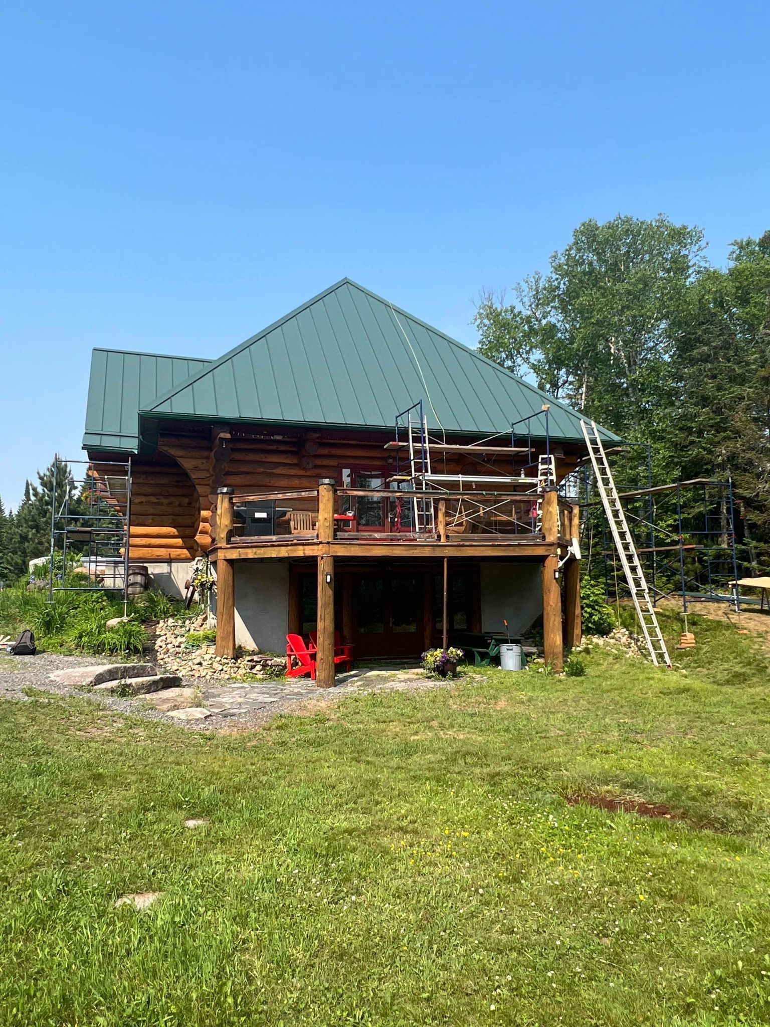 A log cabin with a green roof is sitting in the middle of a grassy field.