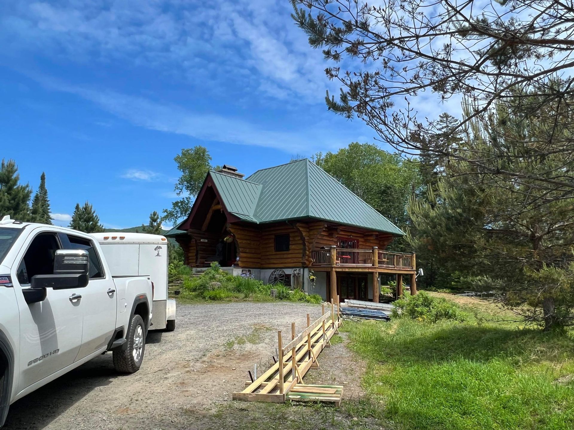 A white truck is parked in front of a log cabin.