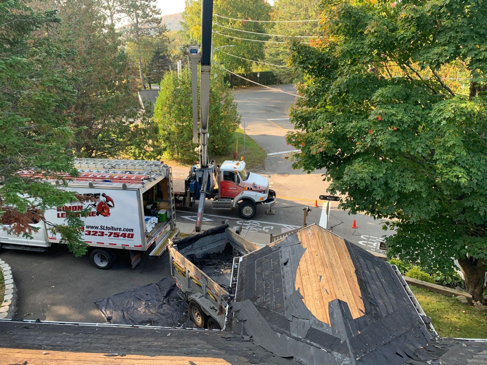 A truck with a crane attached to it is working on a roof.