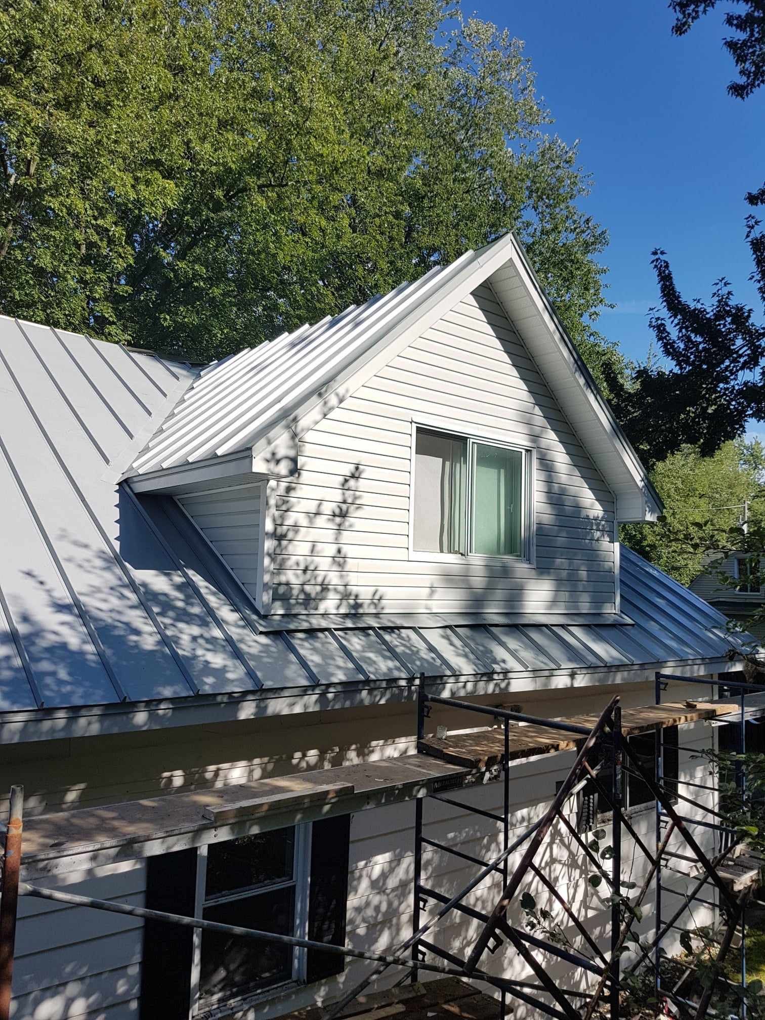 A white house with a metal roof and a window.