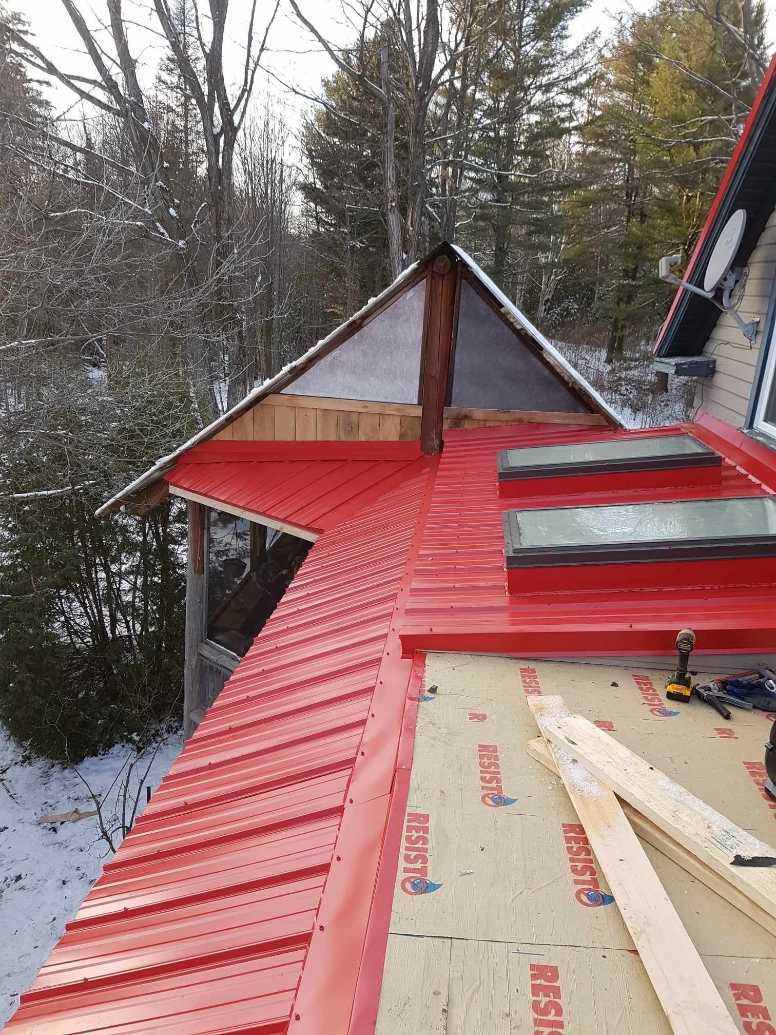 A red metal roof is being installed on a house.