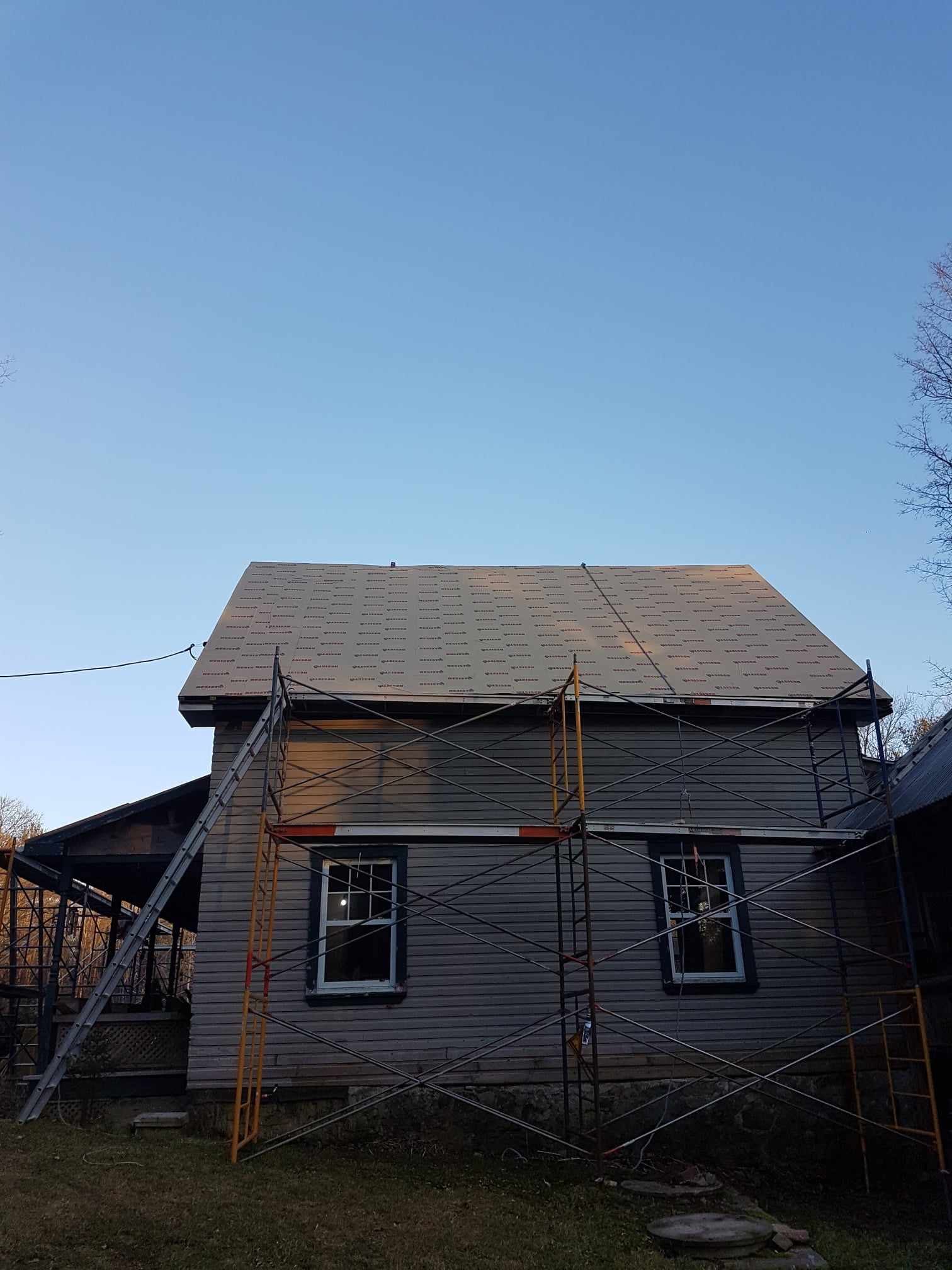A house with a roof that is being repaired with scaffolding around it.