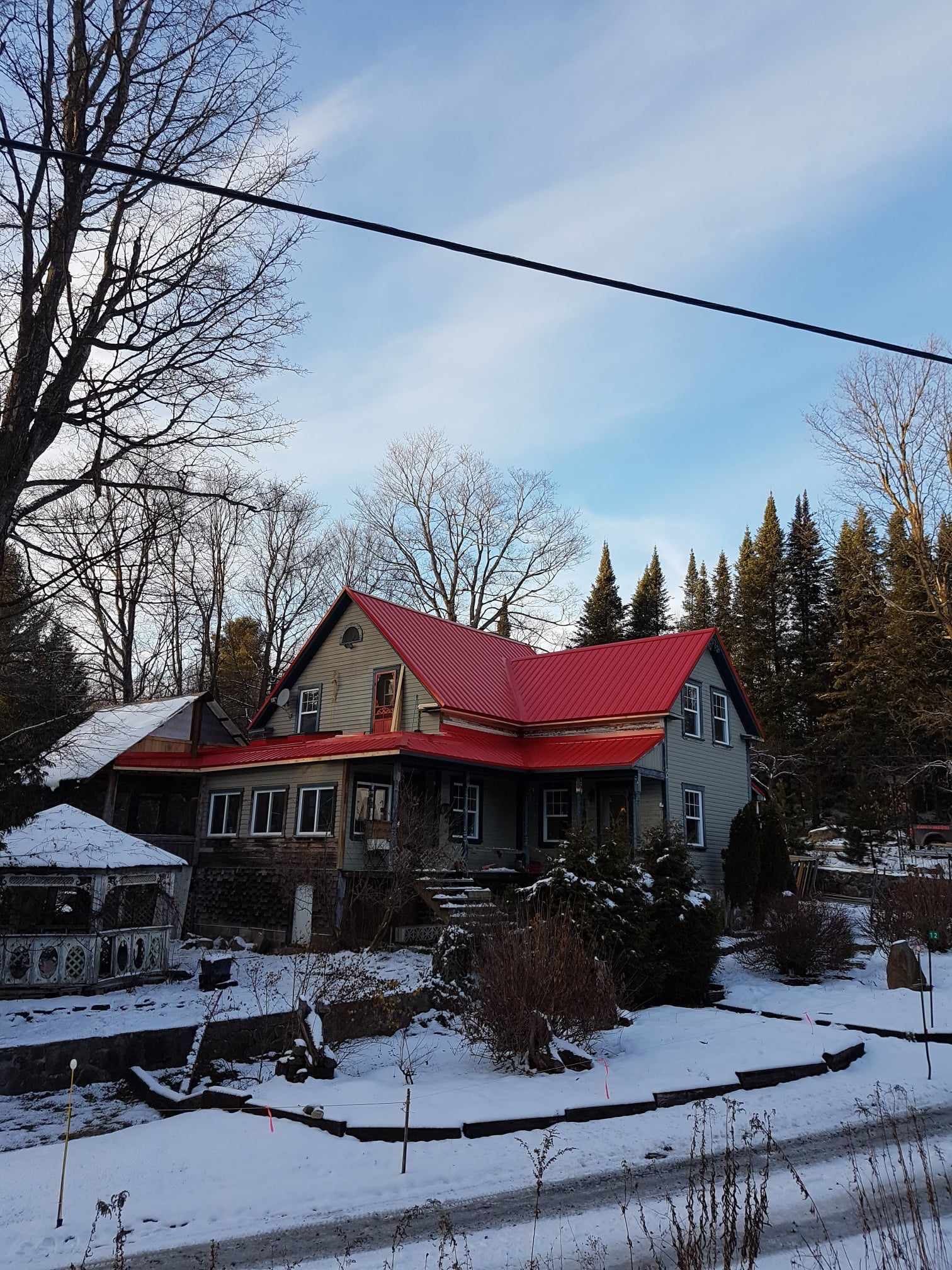 A house with a red roof is surrounded by snow and trees.