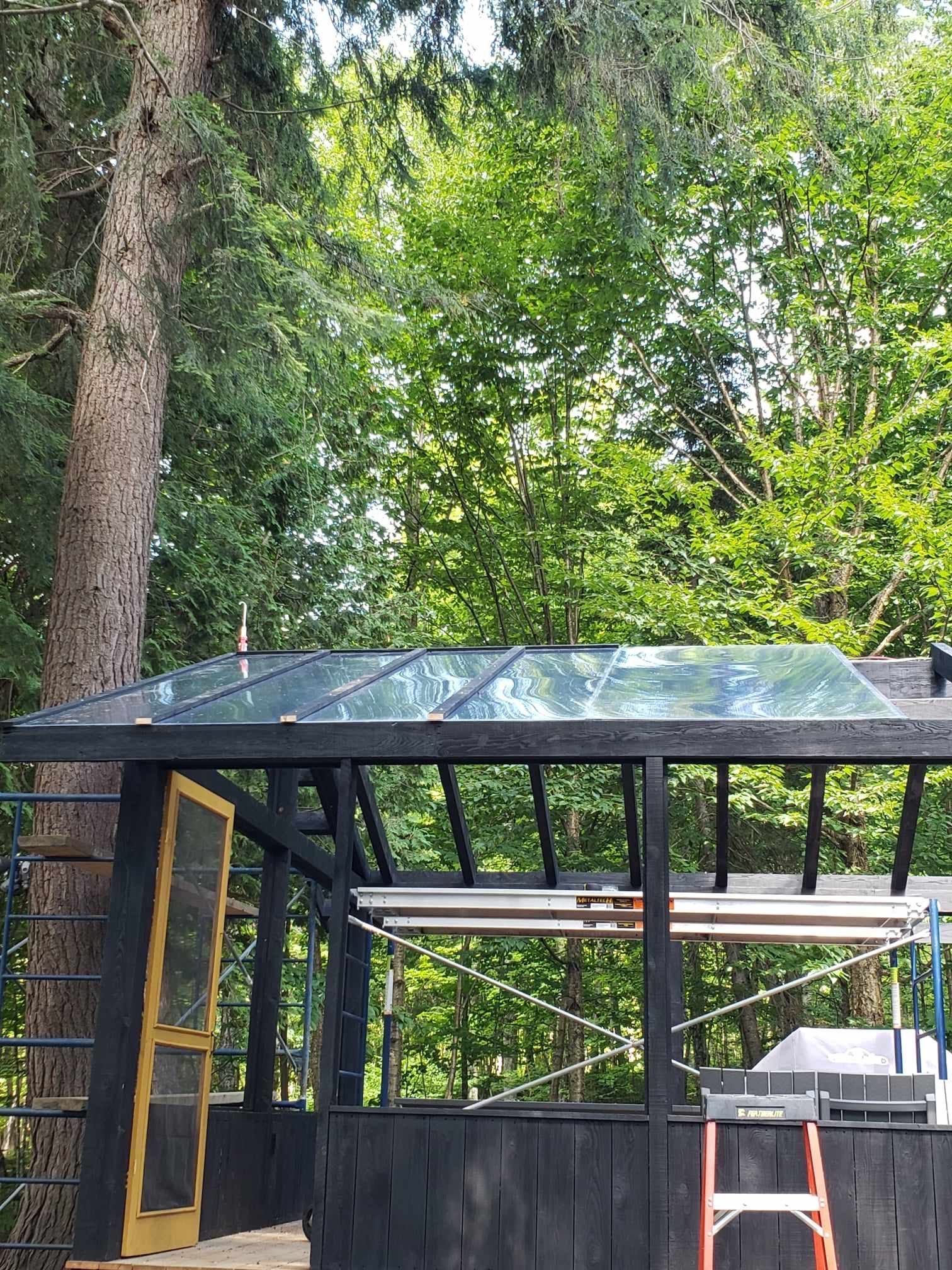 A greenhouse with a glass roof is being built in the woods.
