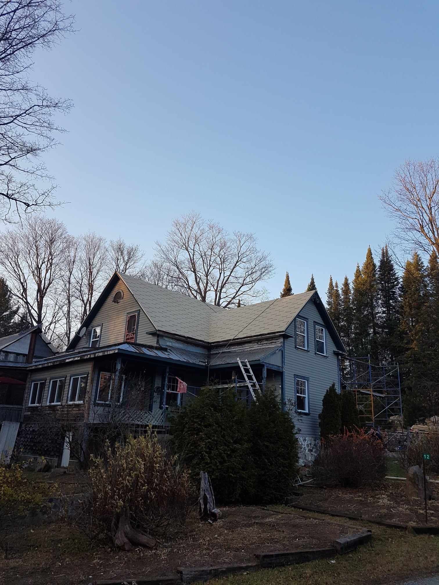 A large house with a white roof is surrounded by trees and bushes.