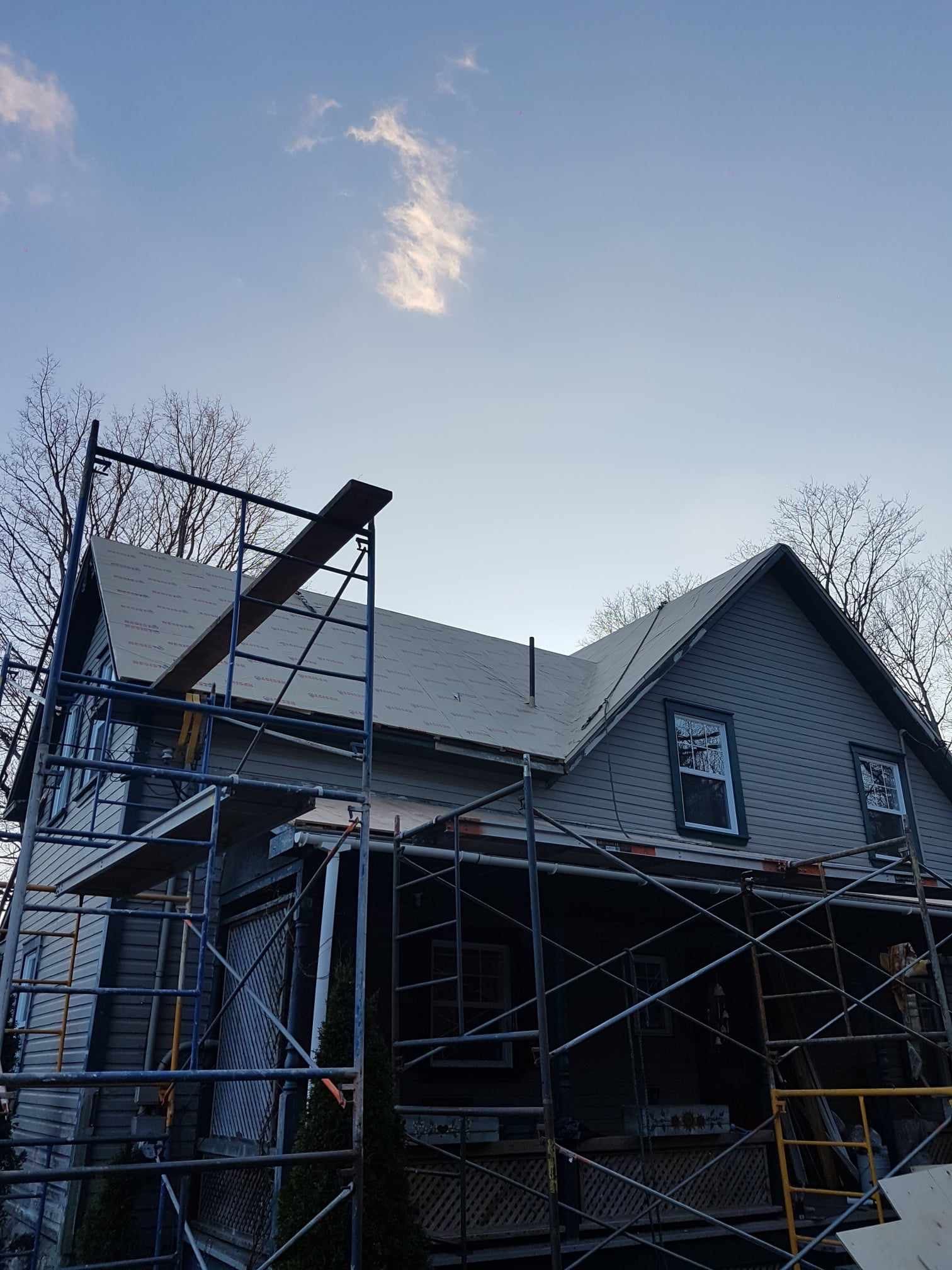 A house with scaffolding around it and a blue sky in the background.
