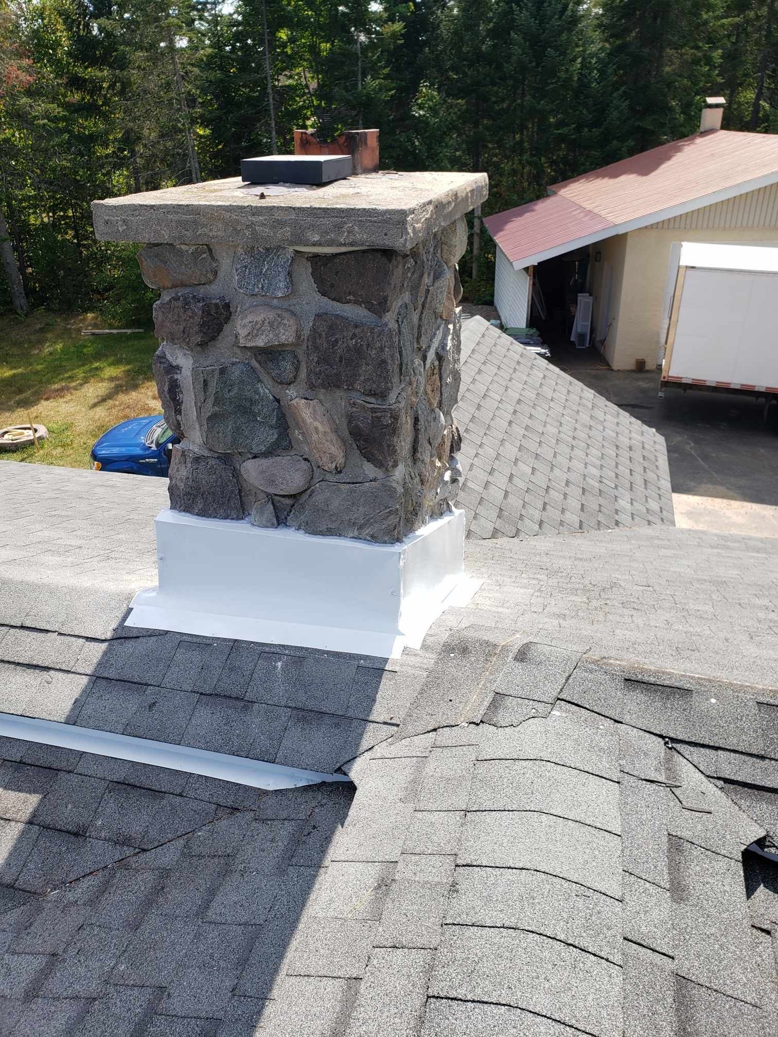 A chimney is sitting on top of a roof next to a house.