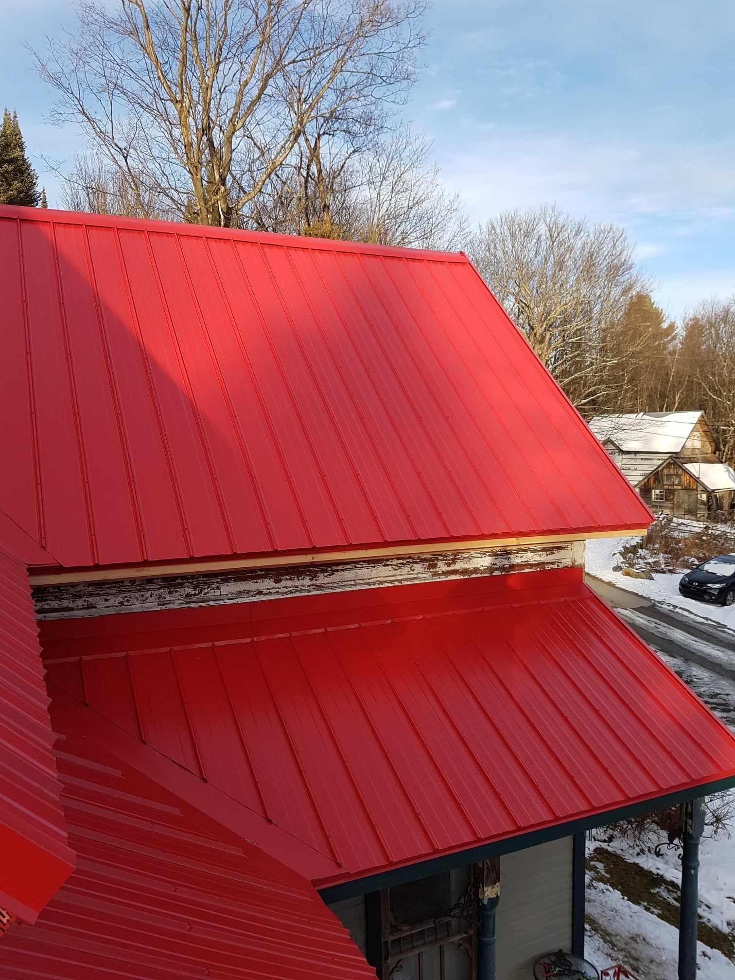 A red metal roof is sitting on top of a house.