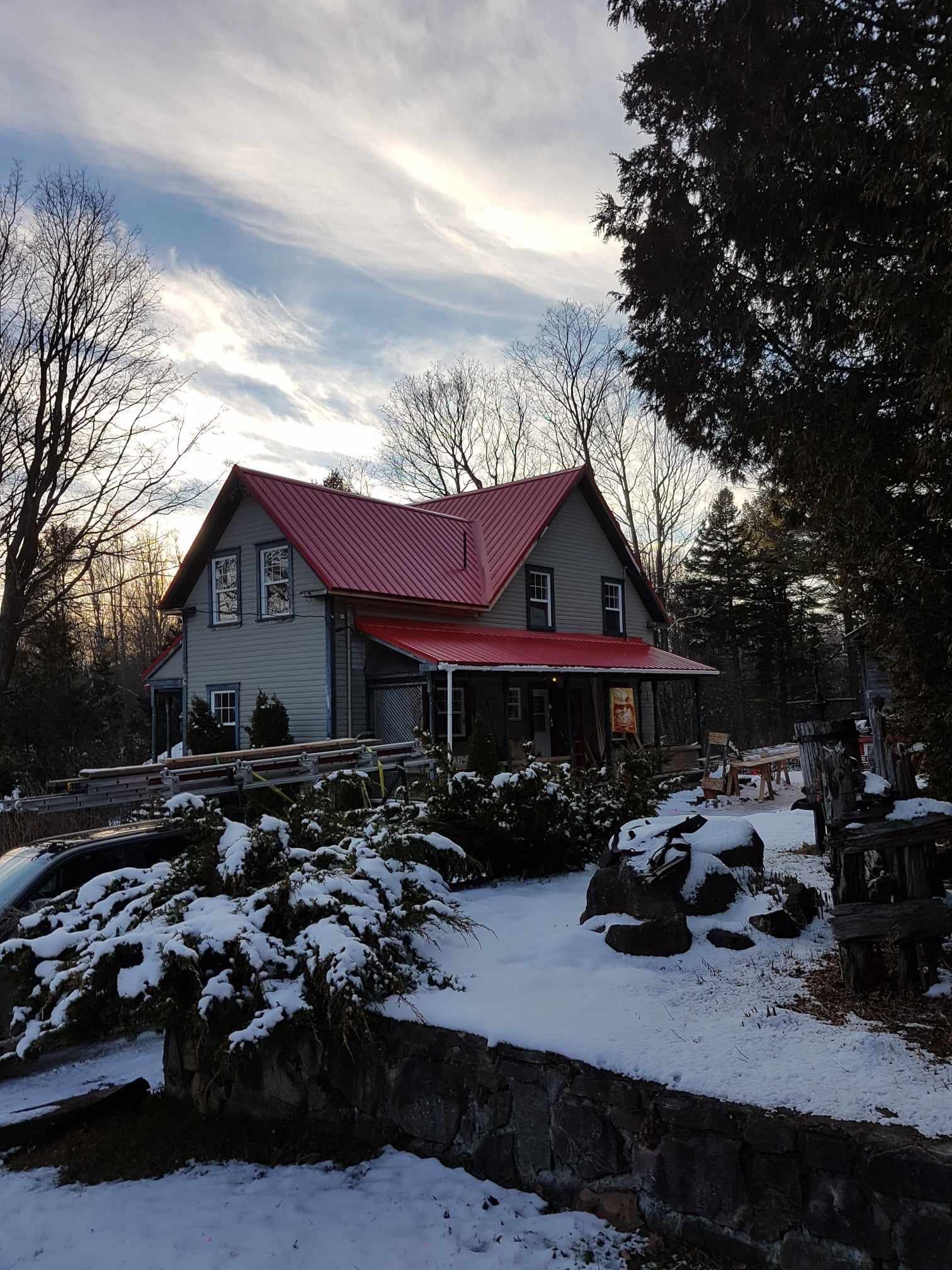 A house with a red roof is surrounded by snow