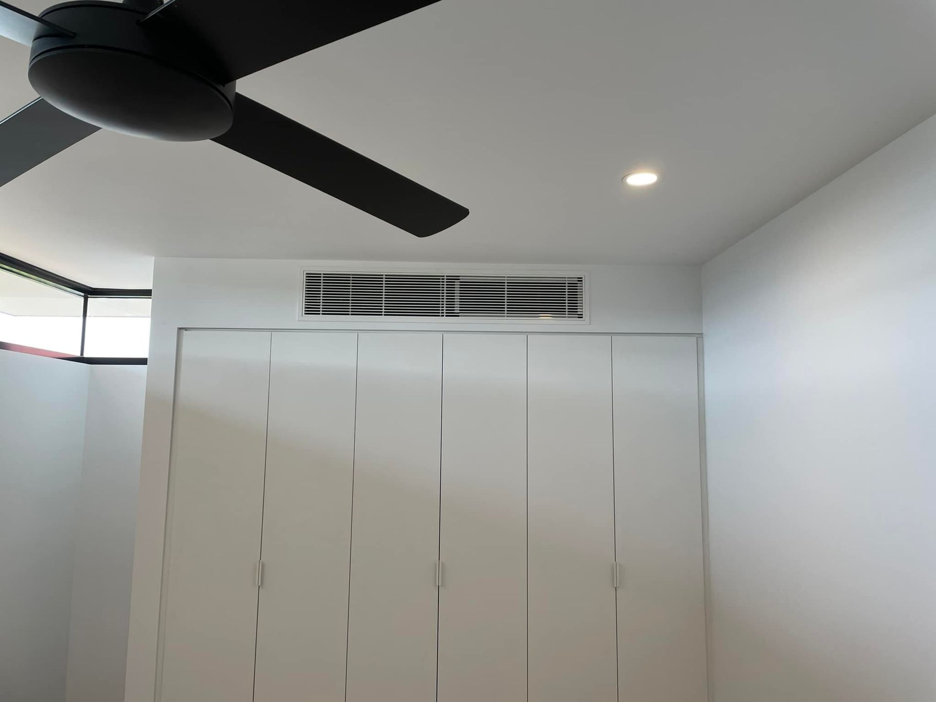 A room with a ceiling fan and white cabinets — Home Air Conditioning Hunter Valley