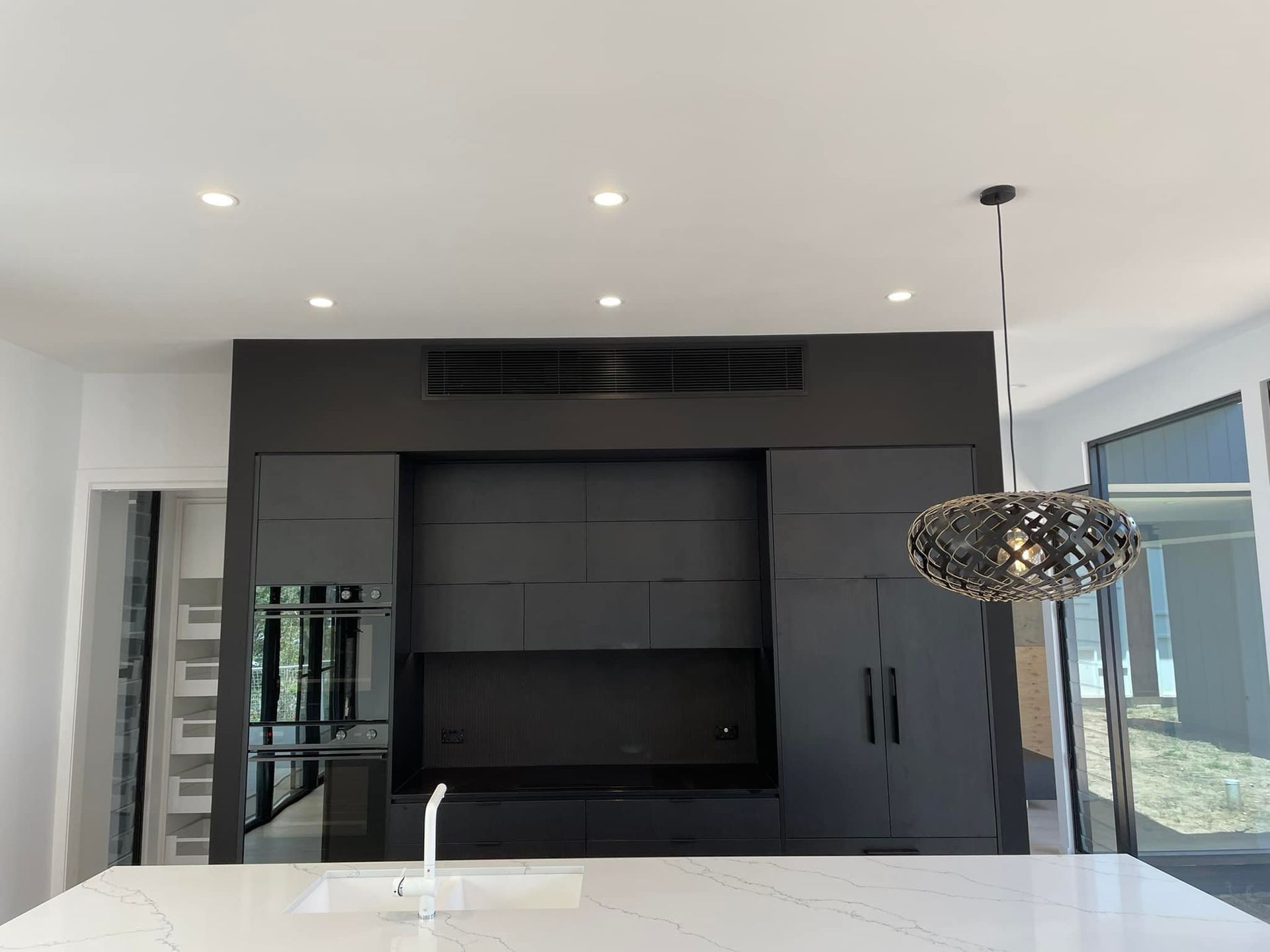 A kitchen with black cabinets and a white counter top — Air Conditioning Service Hunter Valley