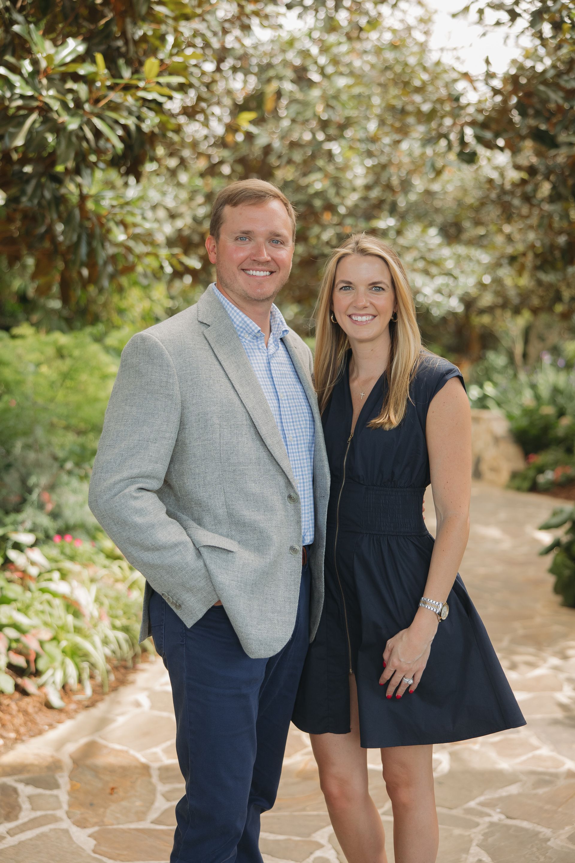Two people standing on a garden path, smiling at the camera.