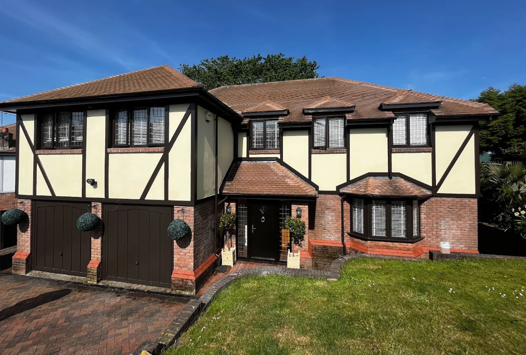 A picture of a large home with Tudor style render painted white