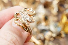 A person is holding a gold ring on their finger.