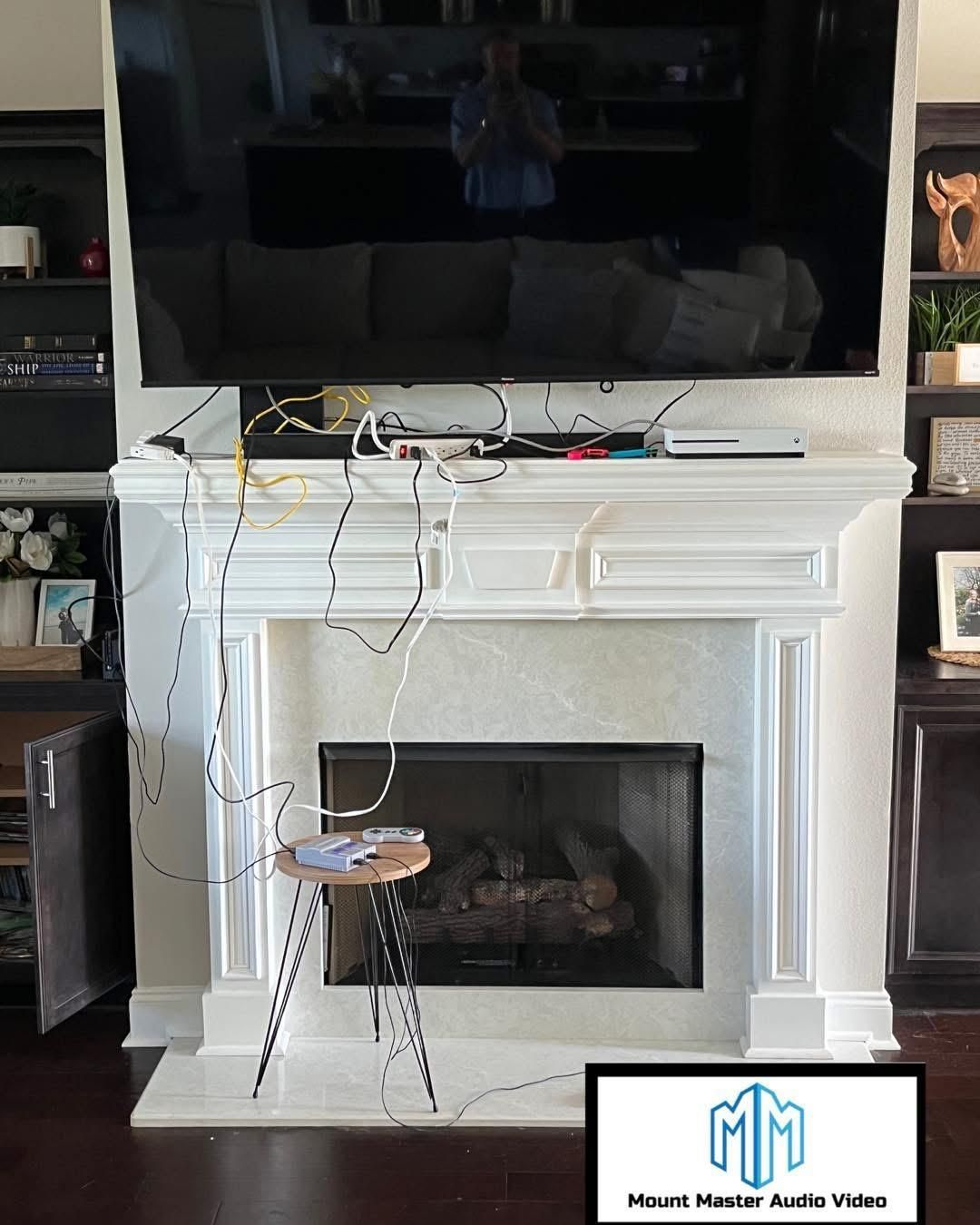 TV mounted above a fireplace with tangled wires, a stool, and built-in shelves. Interior shot.
