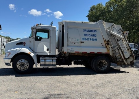 White Saunders Trucking garbage truck parked outdoors on a sunny day. White Saunders Trucking garbage truck parked outdoors on a sunny day.