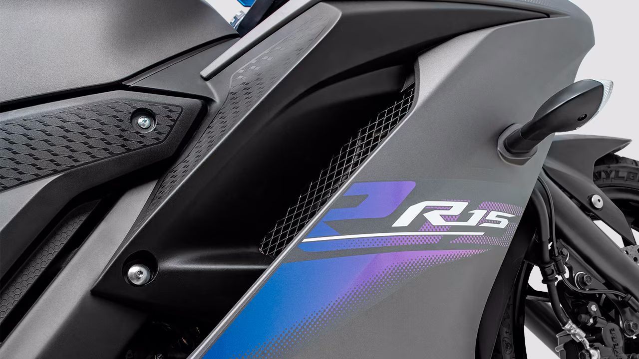 Close-up da carenagem preta de uma motocicleta Yamaha R25 com detalhes em azul e roxo.