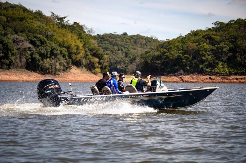 Um jet ski turquesa e branco em águas calmas perto de uma costa verdejante.