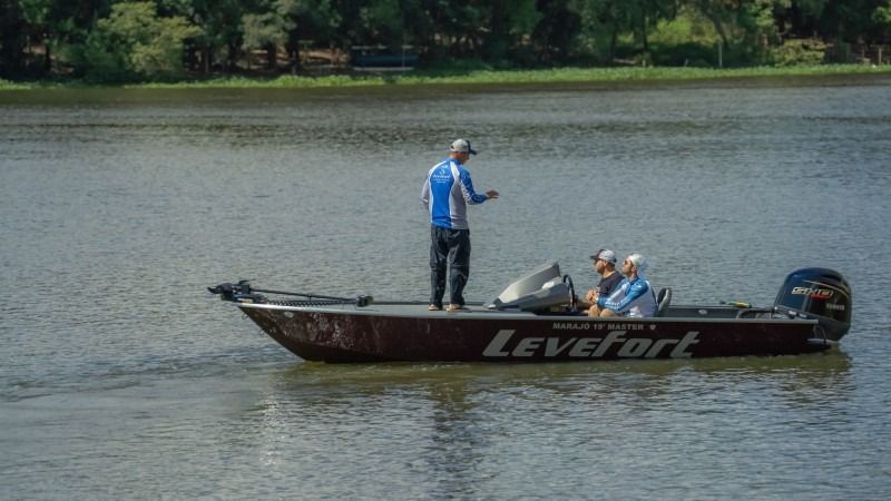 Um jet ski turquesa e branco em águas calmas perto de uma costa verdejante.