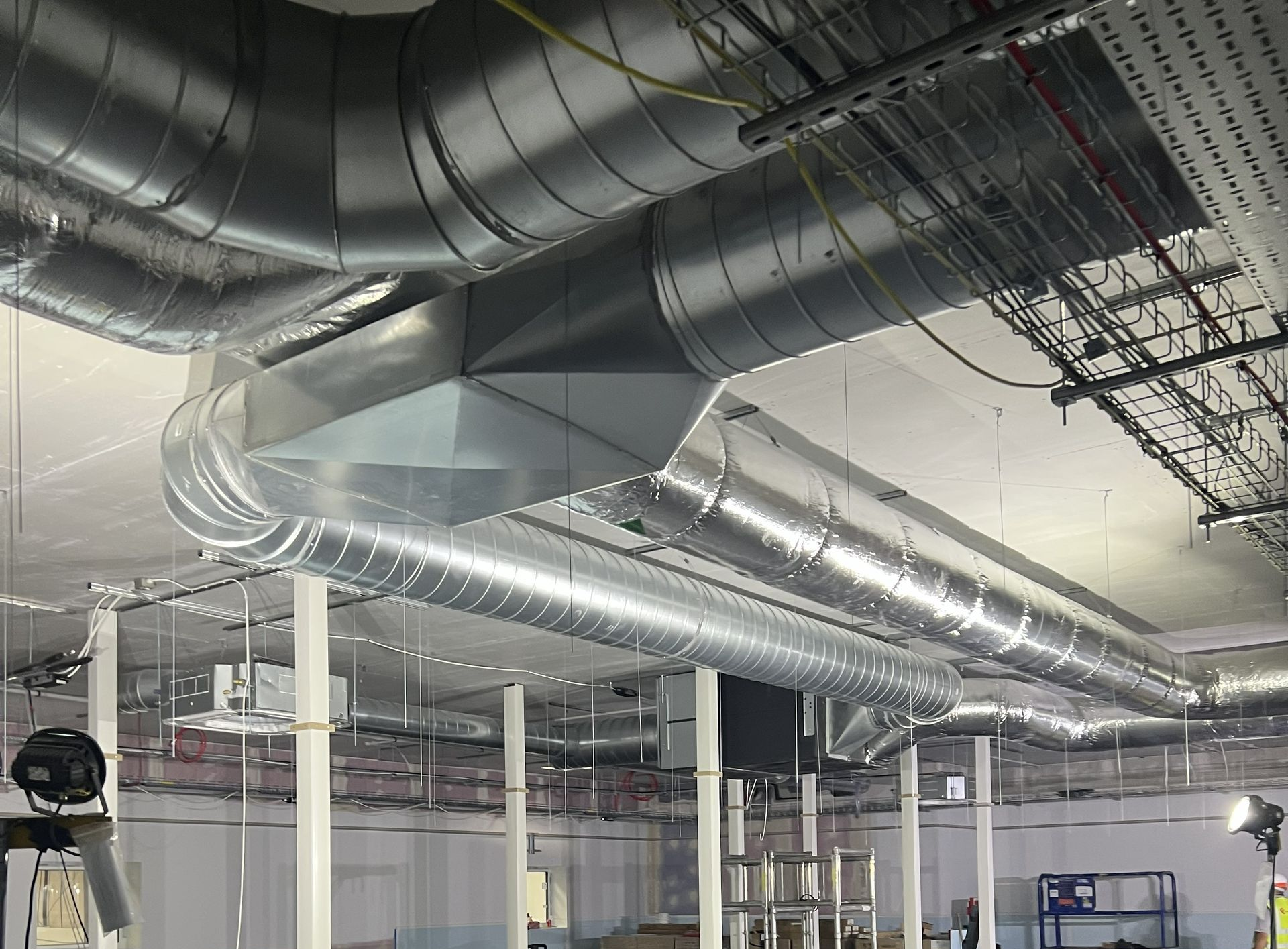 Industrial ceiling with large silver HVAC ducts and piping in a building interior