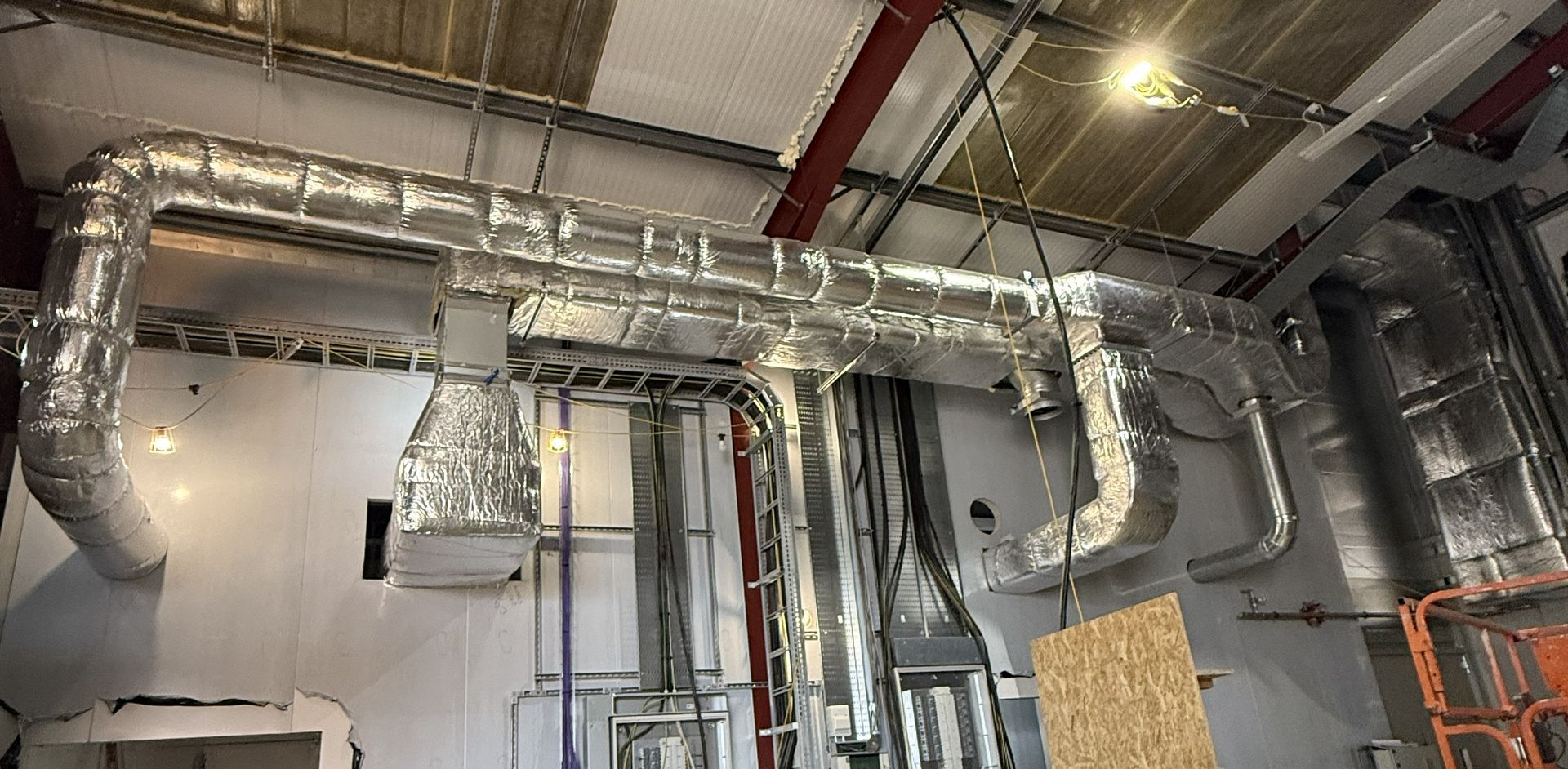 Ceiling HVAC ductwork and silver ventilation pipes in an industrial interior under construction