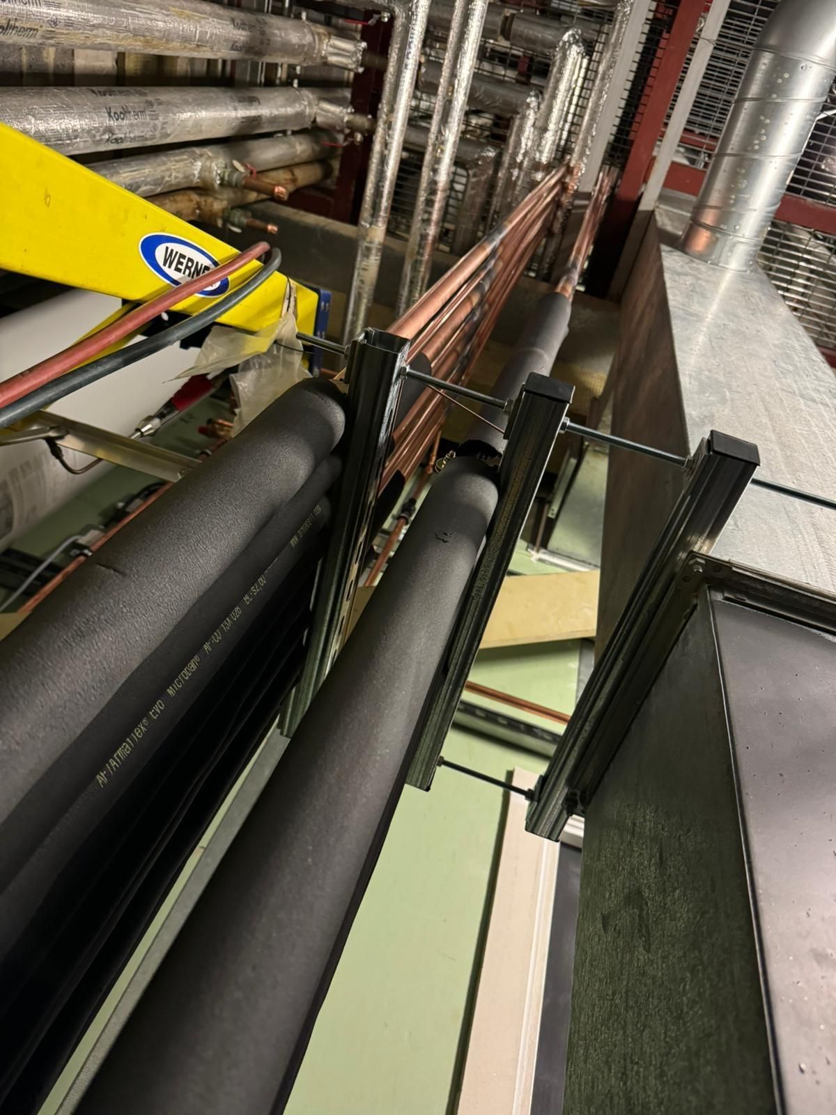 Industrial pipes and machinery in a tight utility space with black and metallic components