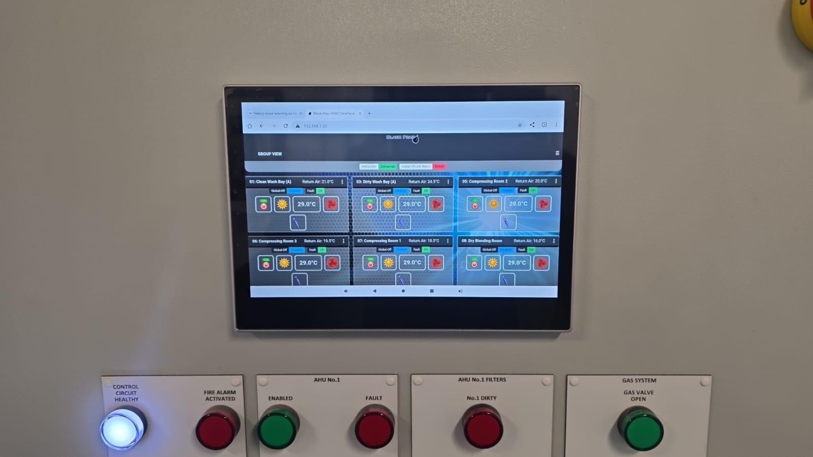 Wall-mounted control screen above colored push buttons in an industrial panel.