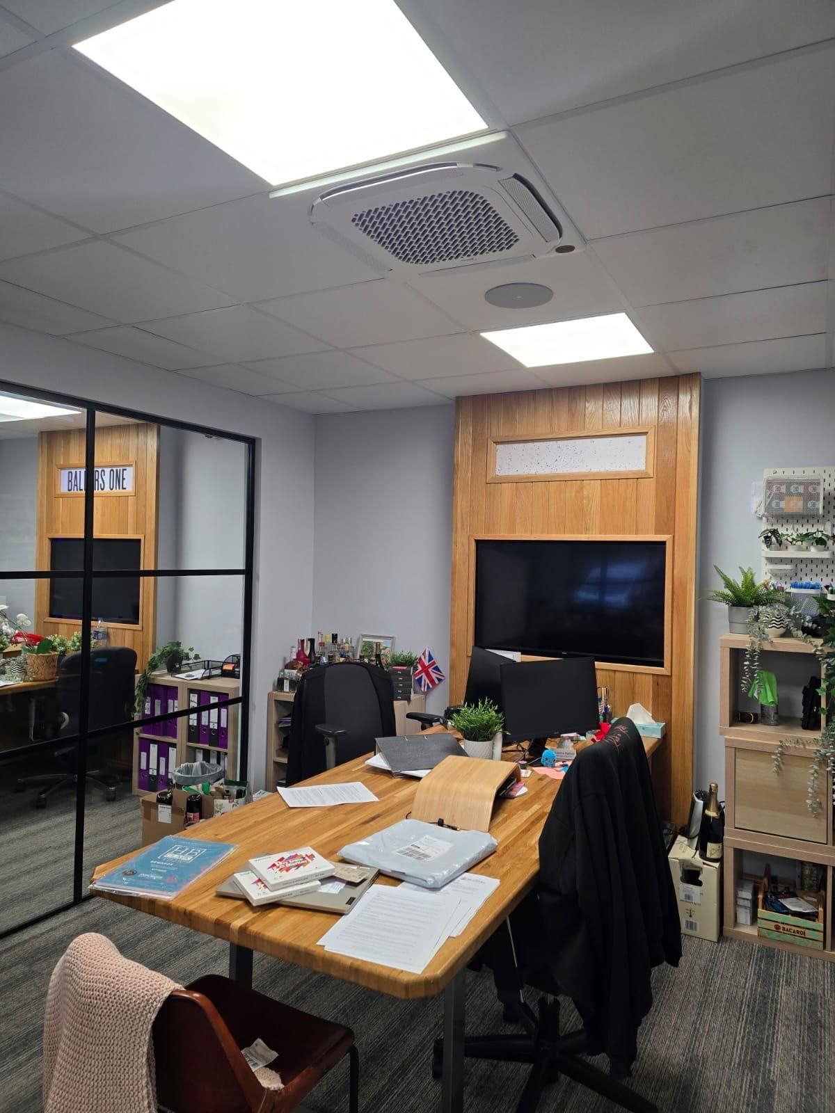 Modern office meeting room with a wooden table, TV screen, chairs, and glass walls