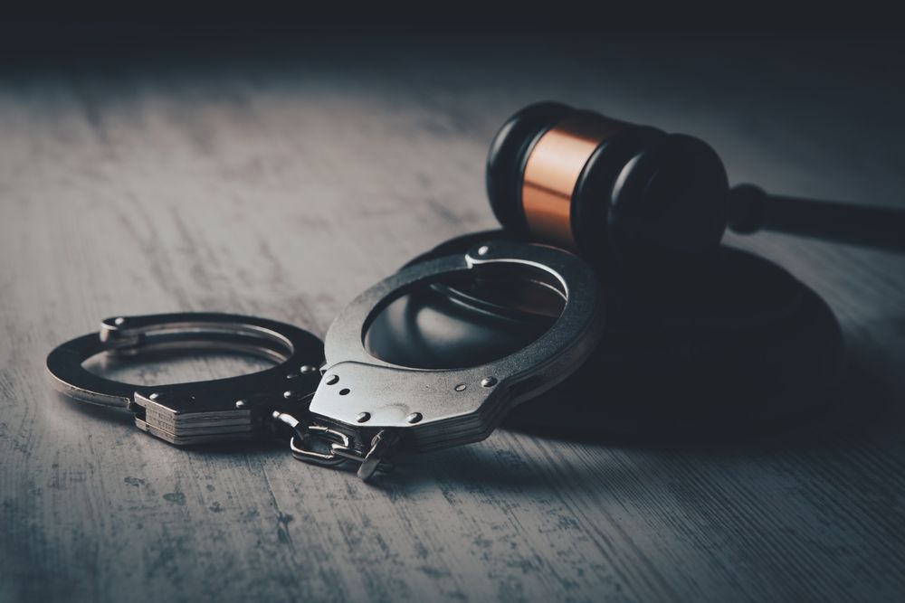 Handcuffs and a gavel on a weathered wooden surface, representing justice and law enforcement.