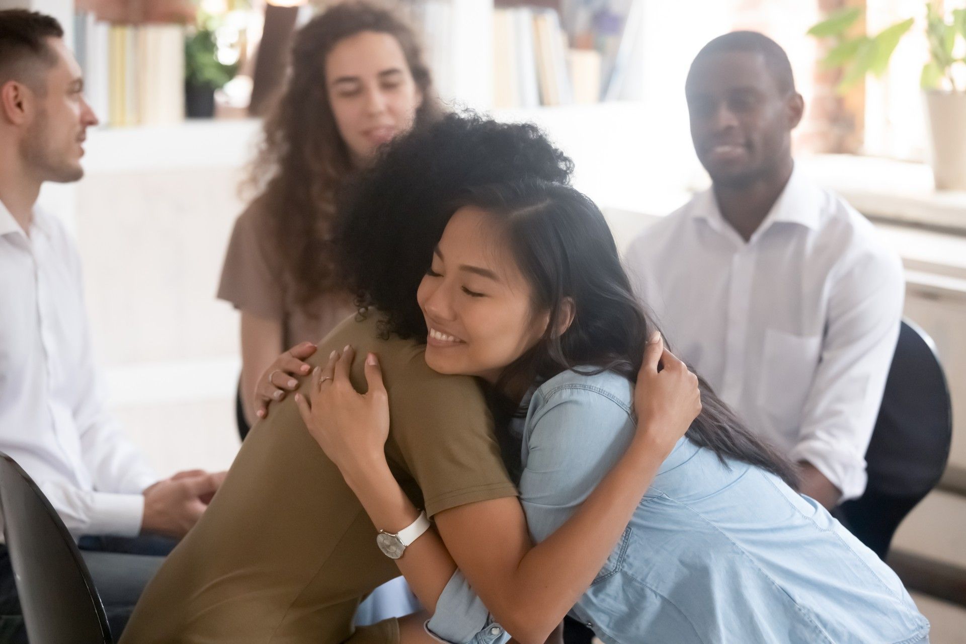 A group of people are hugging each other in a room.
