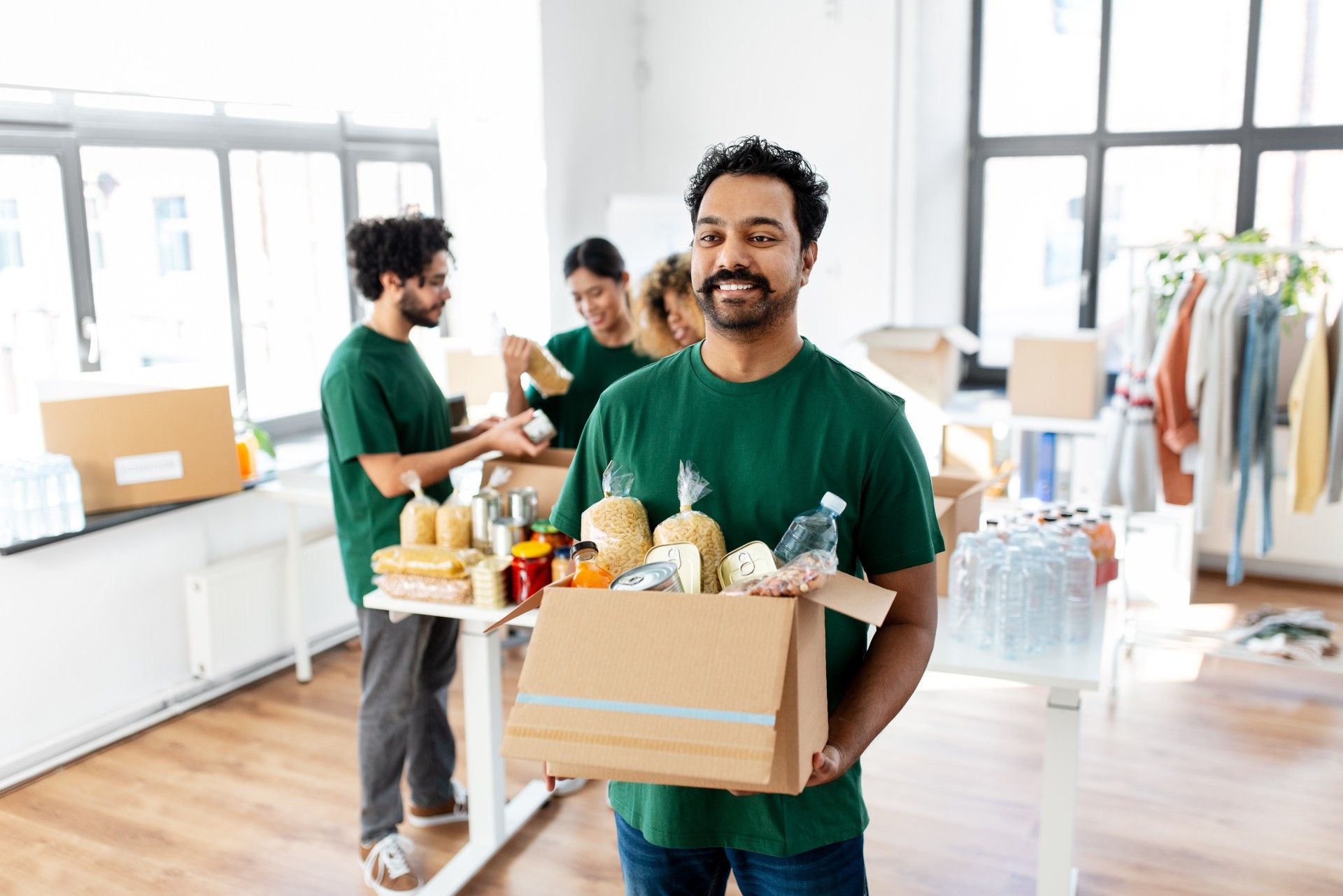 A man is holding a cardboard box filled with food.