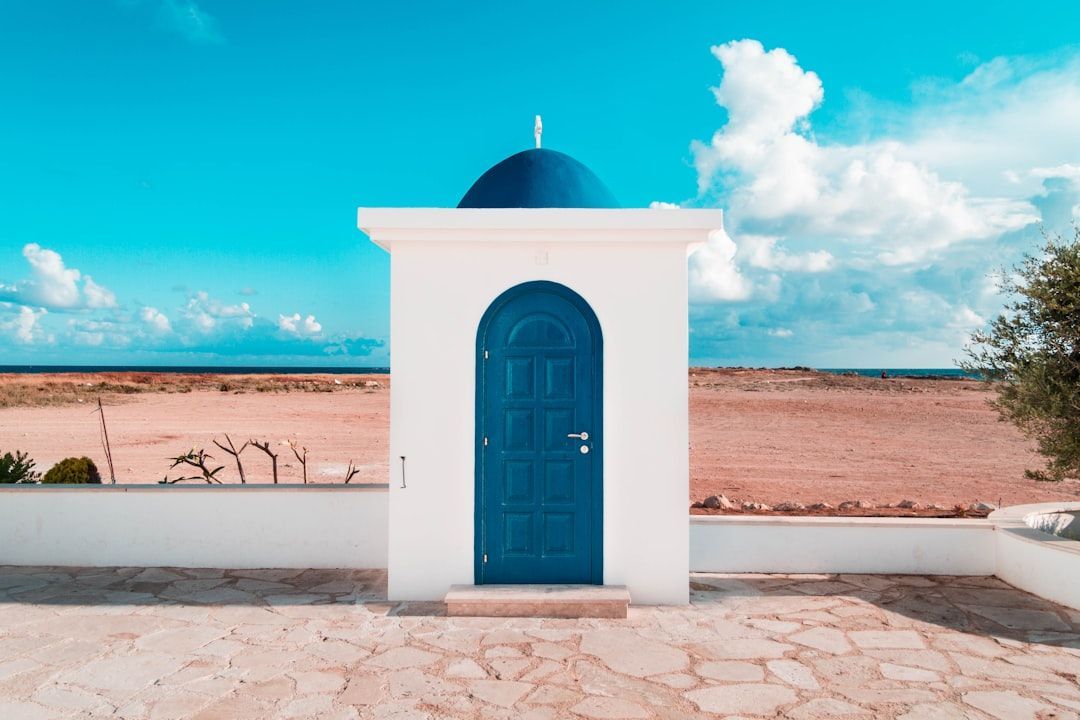 A small white building with a blue door and a dome on top.
