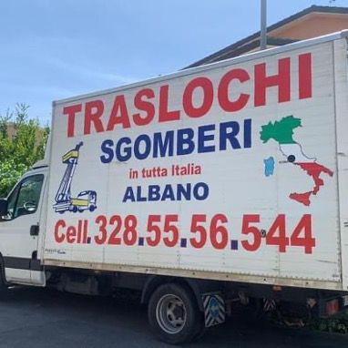 Camion bianco per traslochi con la scritta italiana “TRASLOCHI SGOMBERI”, parcheggiato all'aperto sotto un cielo azzurro.