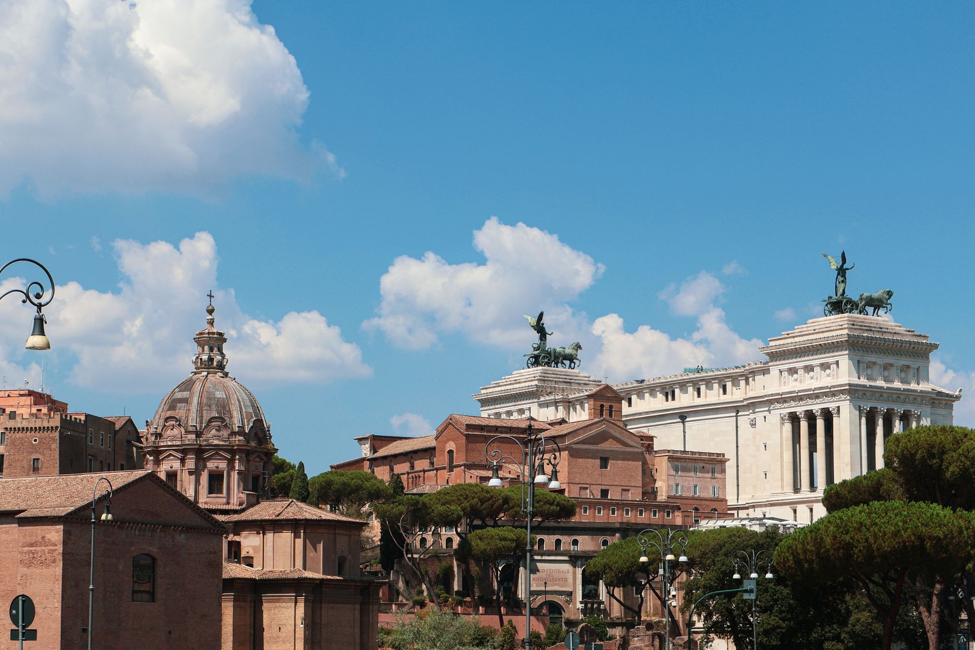 Panorama storico della città con cupole ed edifici classici sotto un cielo azzurro brillante con nuvole.