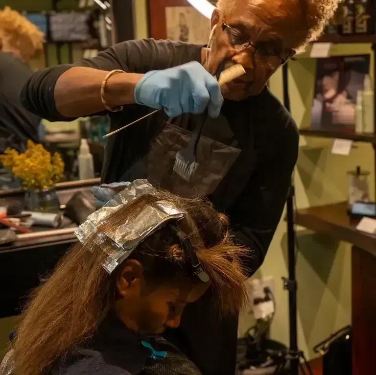 Hairdresser applying foil highlights to a seated client in a salon