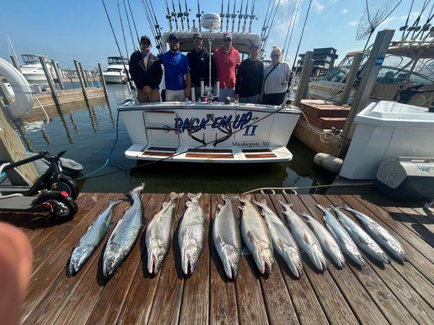 Men on a dock display caught fish. Blue Harbor sign in background.