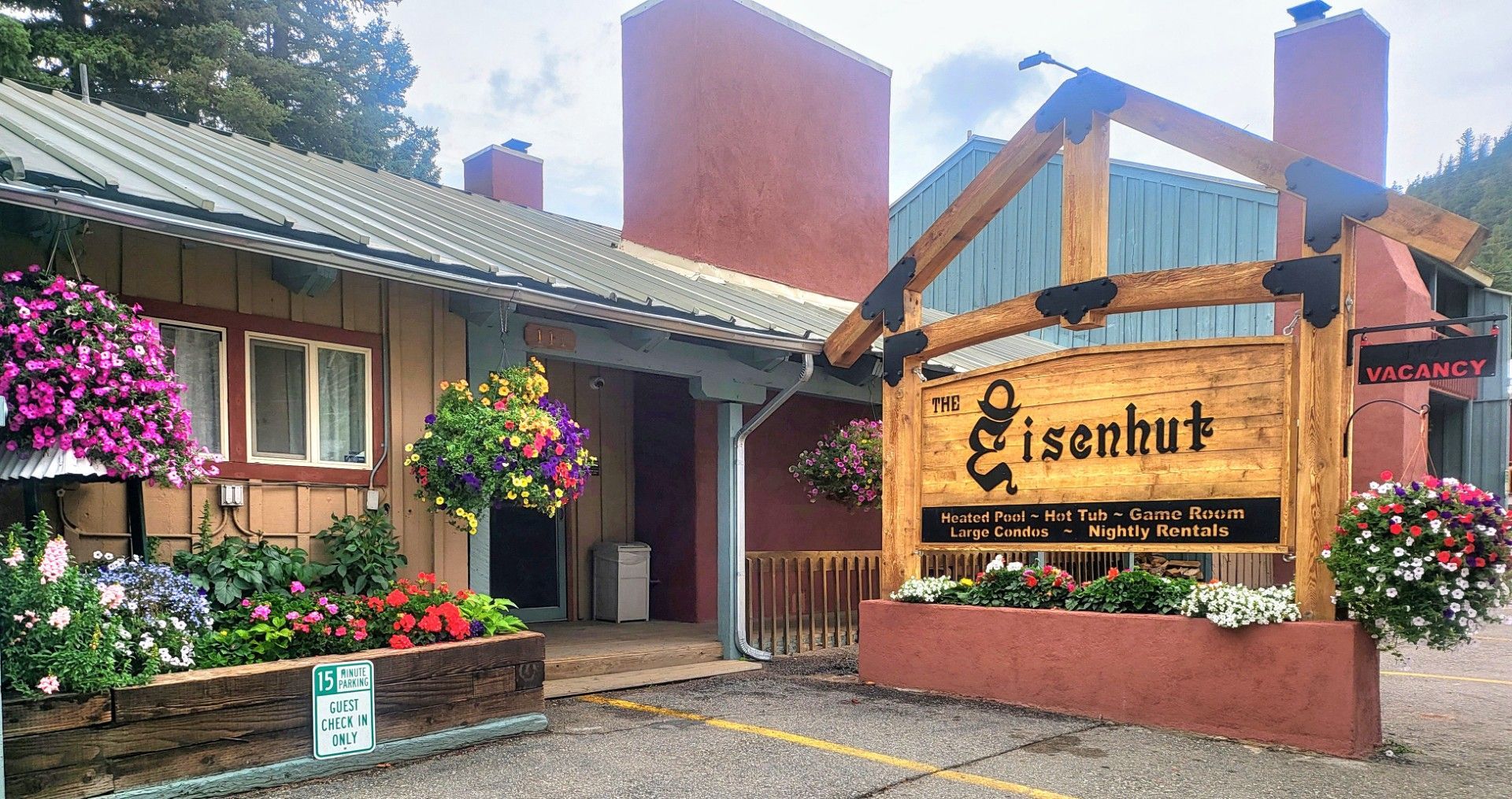 Entrance to Eisenhut, with wooden sign, flower baskets, and red-brick buildings