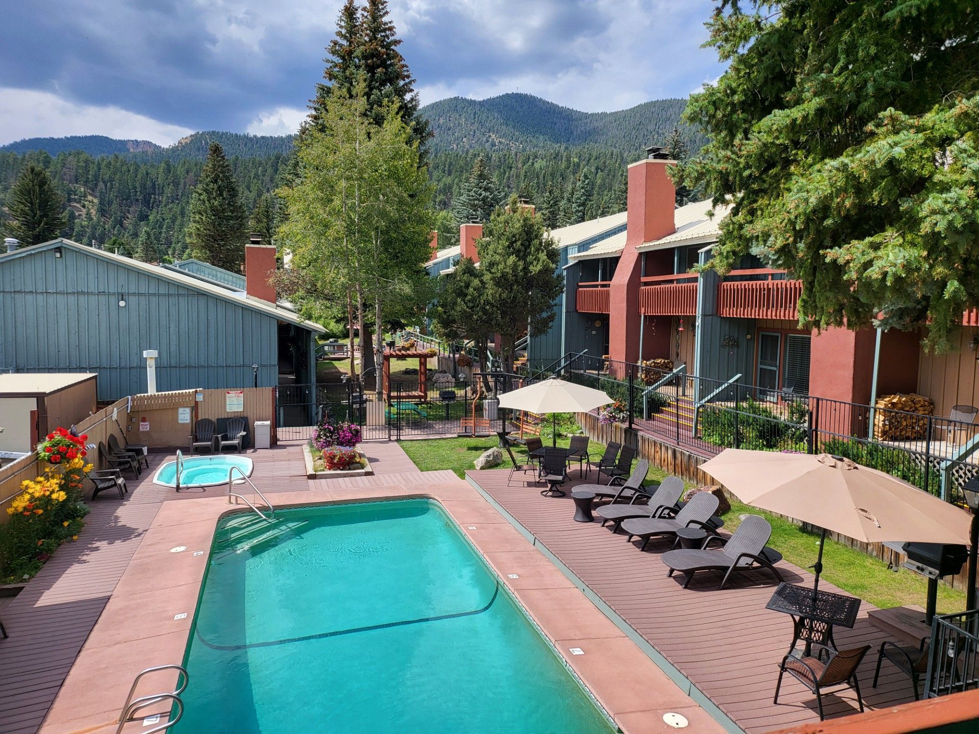 Outdoor pool with lounge chairs and umbrellas in a mountain resort courtyard