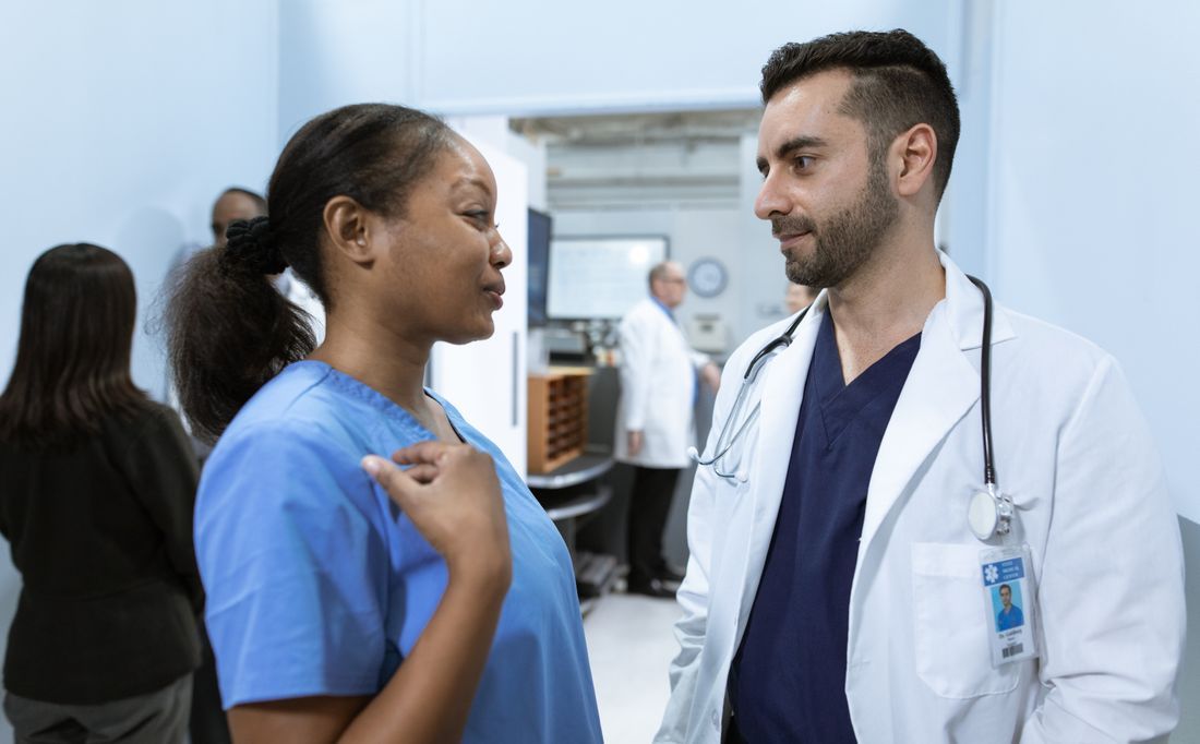 Doctor speaking with a nurse in a hospital hallway