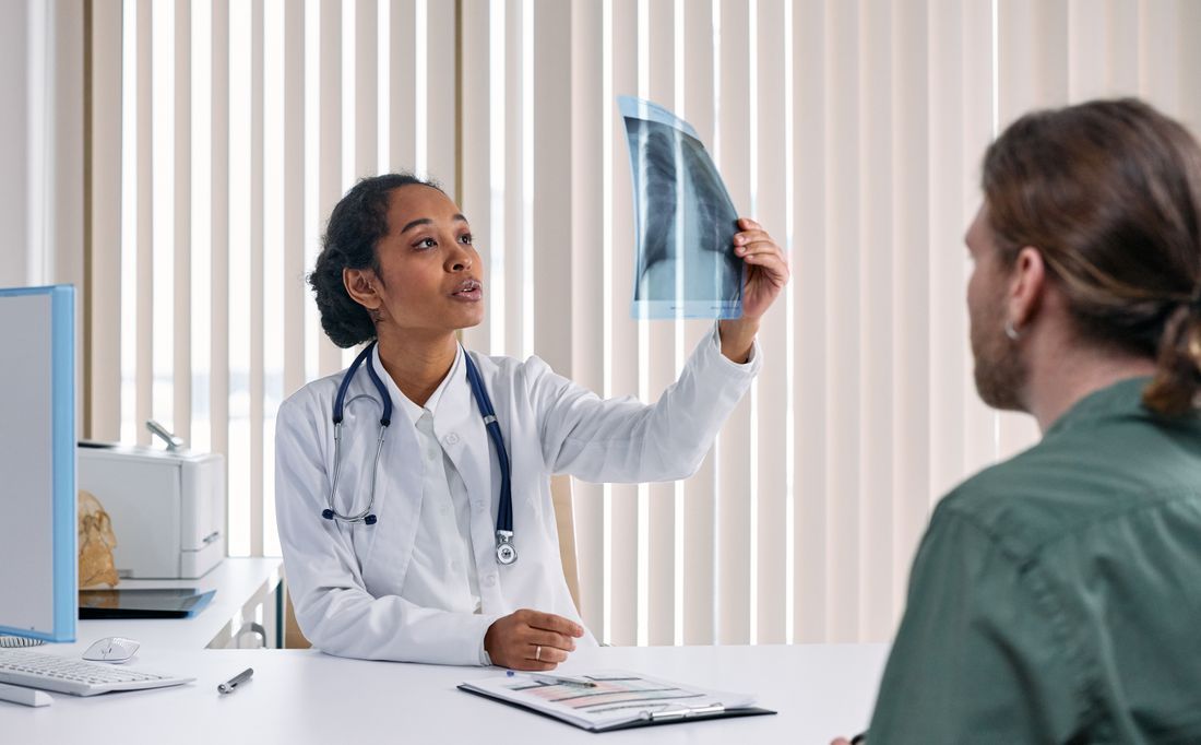 Doctor showing chest X-ray to patient in a clinic consultation room