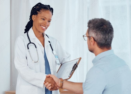 Doctor shaking hands with a seated patient in a bright clinic while holding a clipboard
