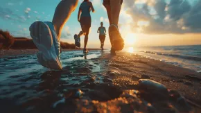 People running through shallow surf at sunset, with waves splashing around their feet.