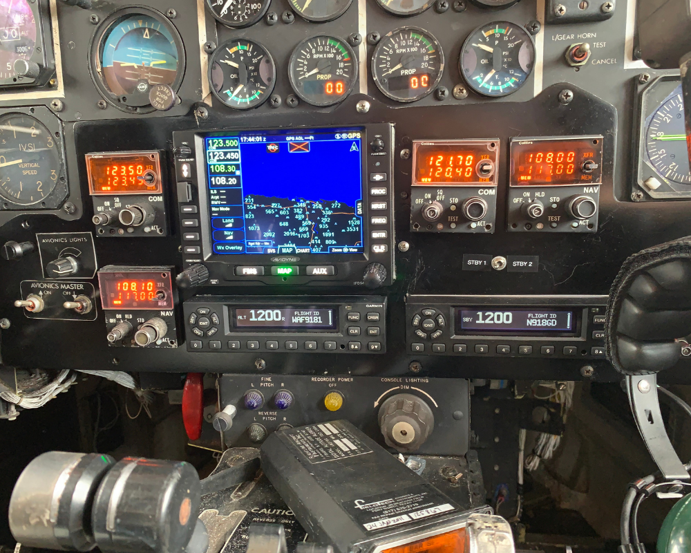 Aircraft cockpit instrument panel showing gauges, radios, and a GPS screen.