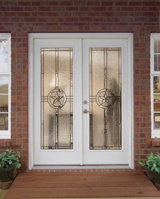 White double front doors with decorative glass panels set in a red brick entryway.