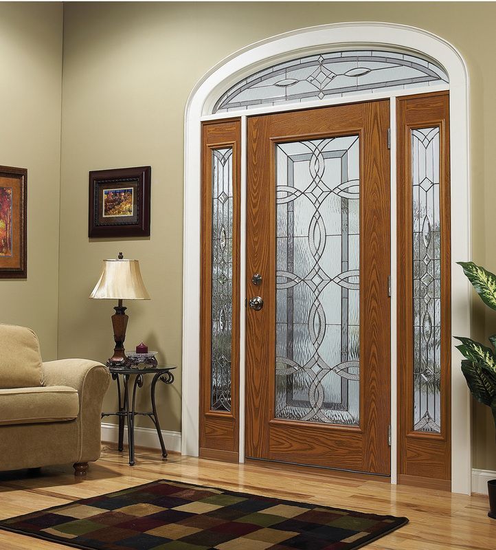 Elegant wooden front door with etched glass panels in a beige living room, beside a lamp and sofa