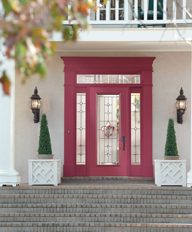Front entrance with magenta double doors, sidelights, lanterns, and potted evergreens at the top of steps