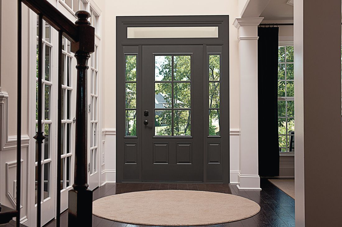 Front entryway with dark double doors, white trim, and a round beige rug
