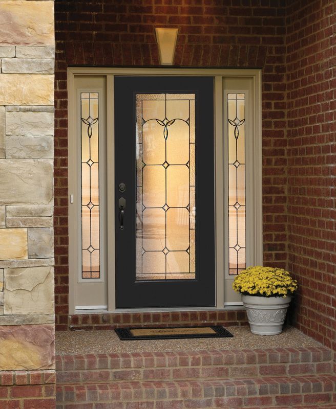 Front porch with a dark front door, brick steps, and a potted yellow mum beside it.