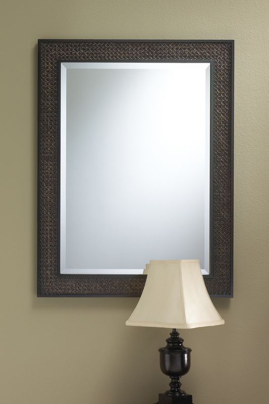 Framed wall mirror above a beige table lamp against a tan wall