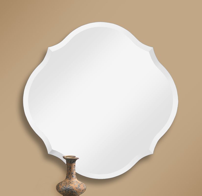 White ornate mirror on a beige wall with a decorative vase at the bottom center